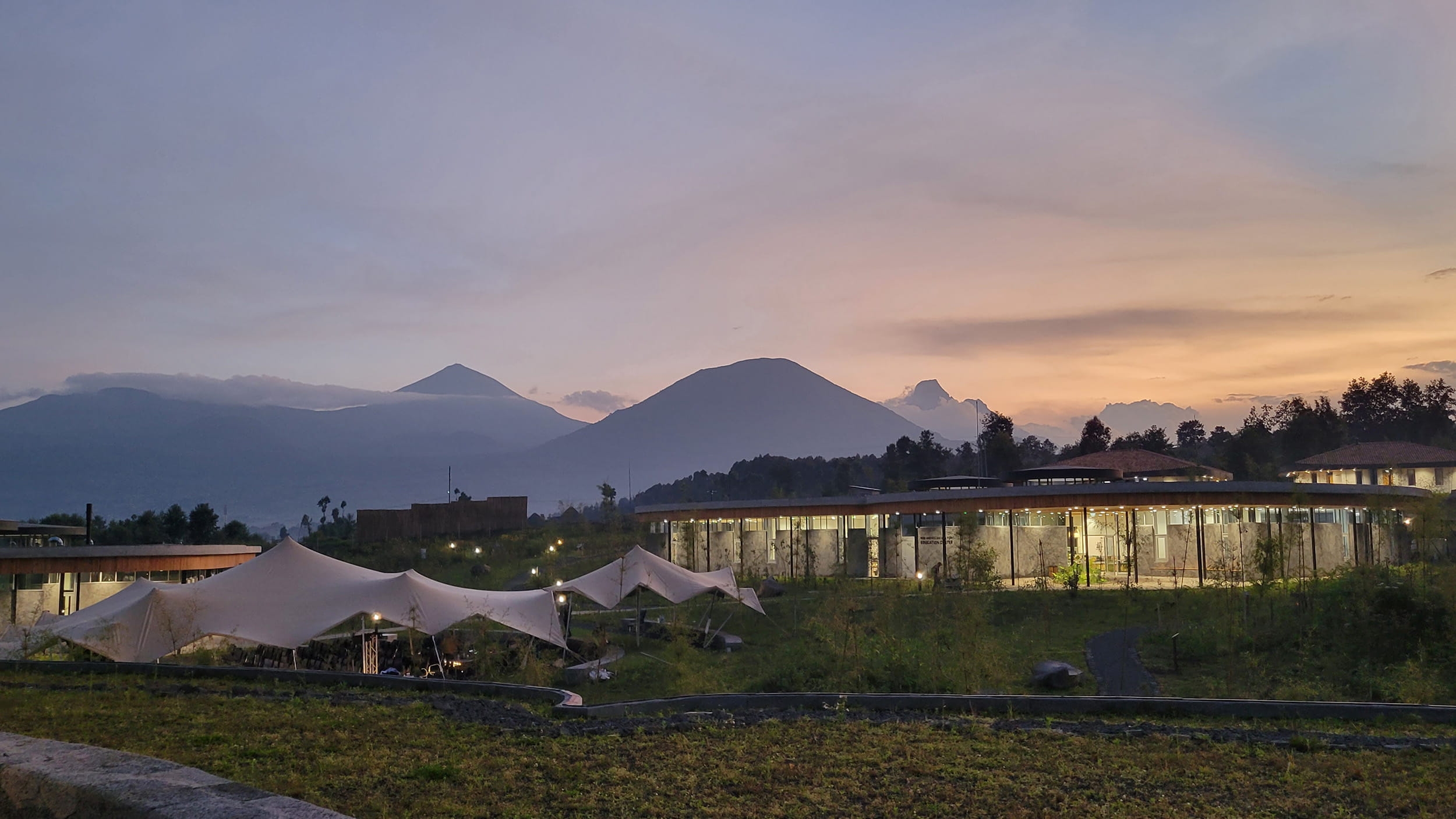The Ellen DeGeneres Campus of the Dian Fossey Gorilla Fund at sunset, showing sustainable campus buildings integrated into the surrounding Rwandan landscape.