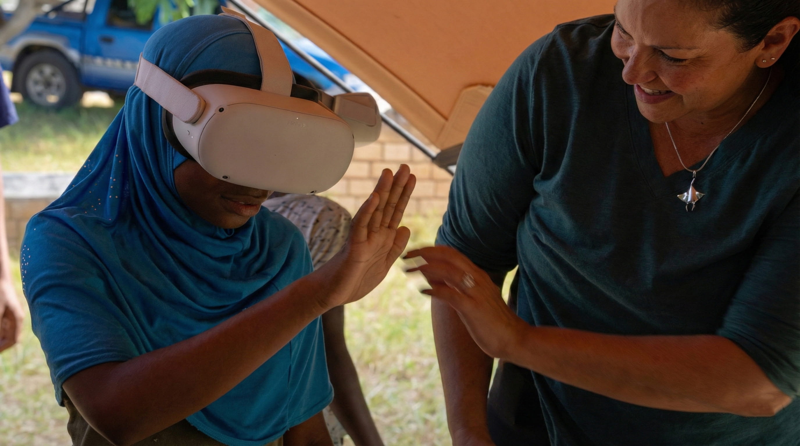 A child wearing a VR headset reaches out while experiencing an immersive underwater film, guided by an adult during a marine learning activity.