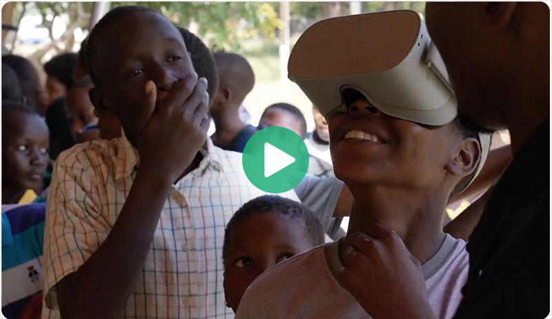 A child reacts with a smile while watching an immersive underwater VR film, learning about marine life through a virtual experience.